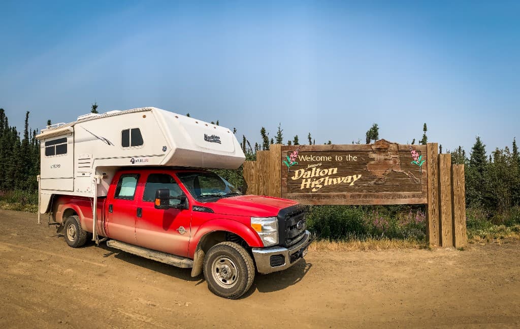 Glen's truck camper beside the Alaska Highway sign.